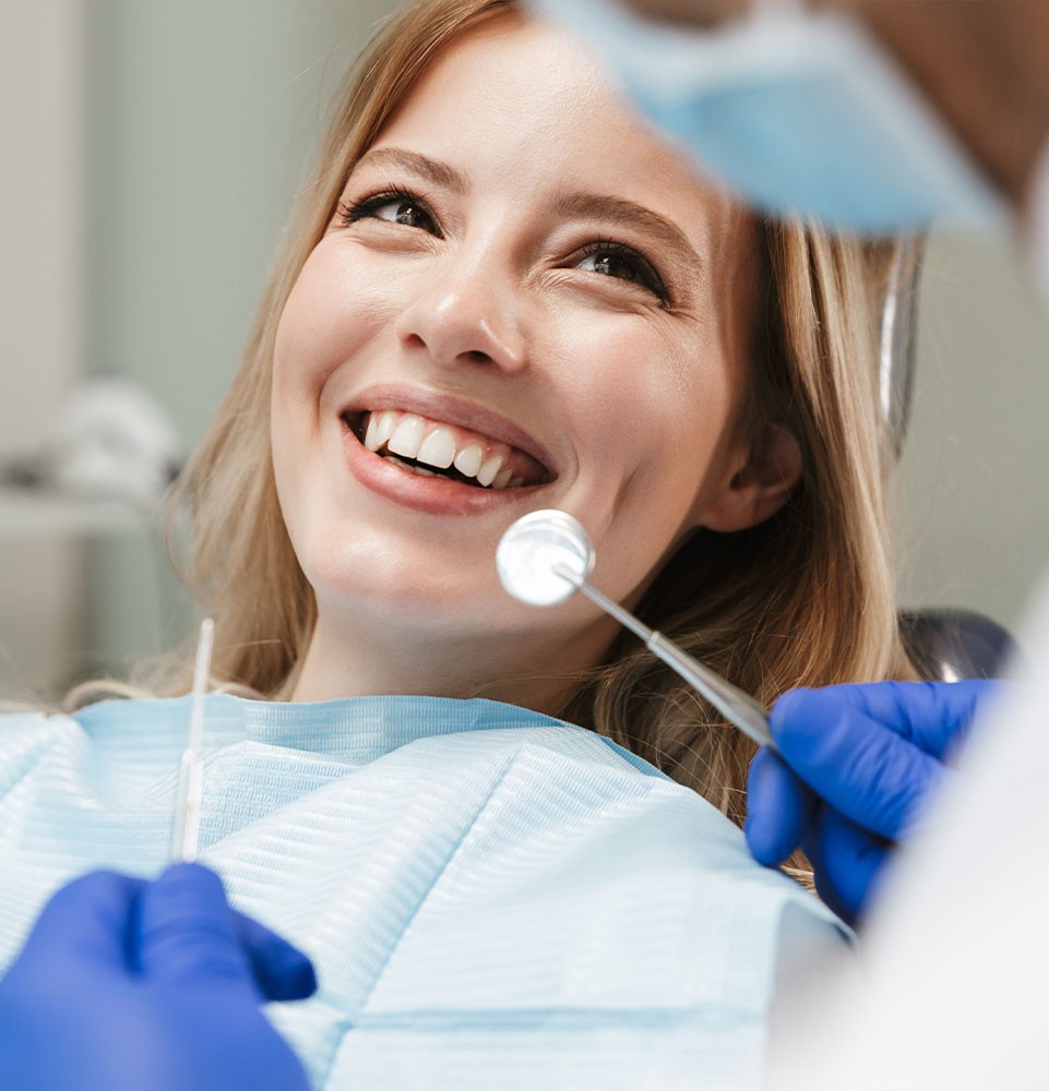 dental patient smiling in exam chair with tools held up