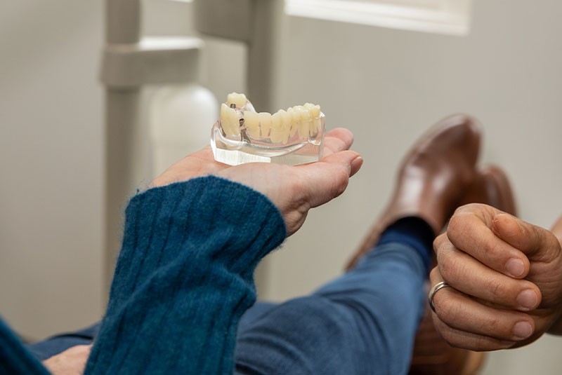 patient holding dental implant model within the dental office